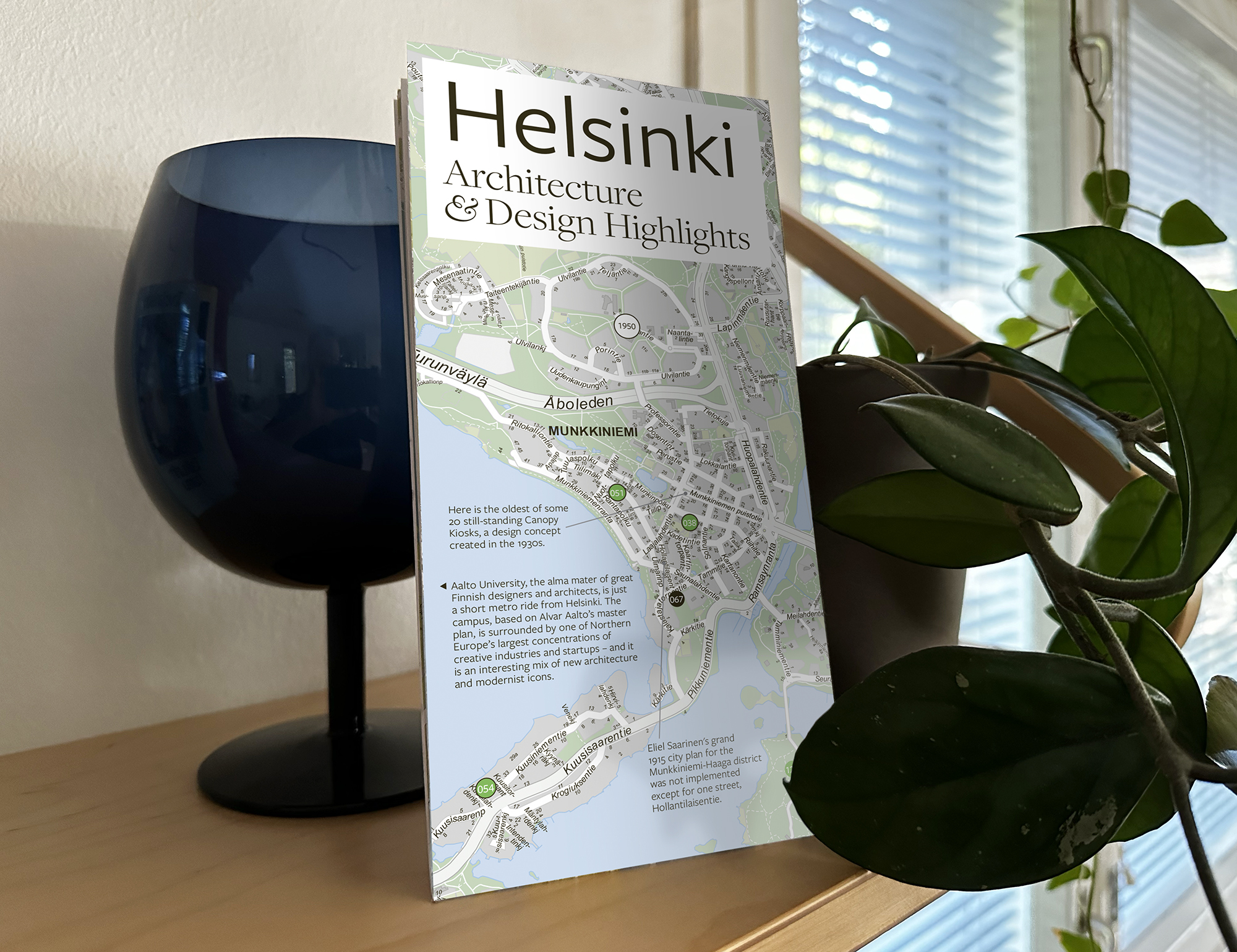 A map in a bookshelf with a blue wine-glass-like vase and a plant