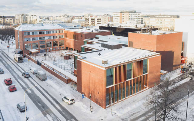 An aerial view of the entire red-brick campus set against a dense urban view.