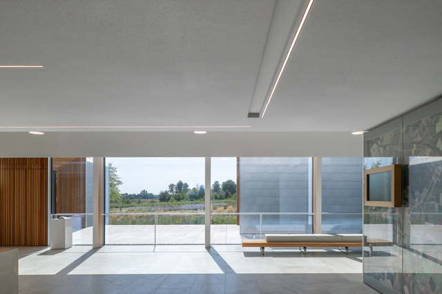 An interior photo featuring a pale stone floor, an ethereal atmosphere, and large windows overlooking a green landscape.
