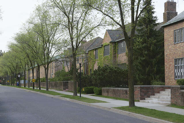 A row of red-brick houses along a street with trees