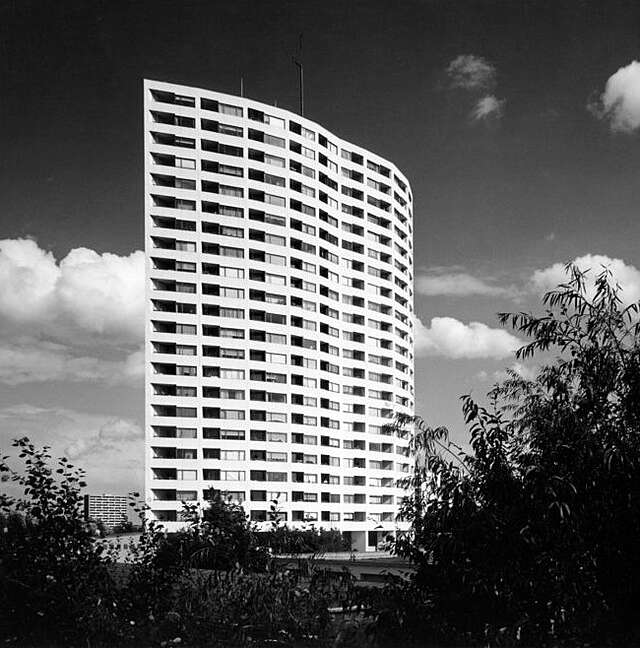 BW photo of a white, curving highrise with balconies