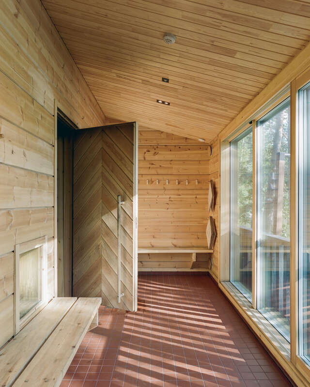 A wooden interior walkway with windows along the right wall and an open door on the left.