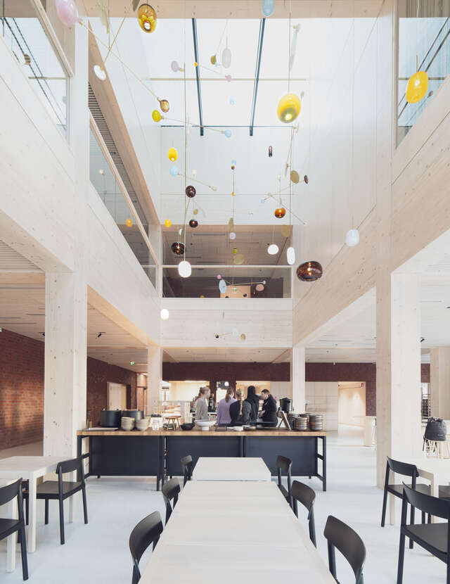 A high, light-filled canteen space with a glazed roof and timber-clad interior.