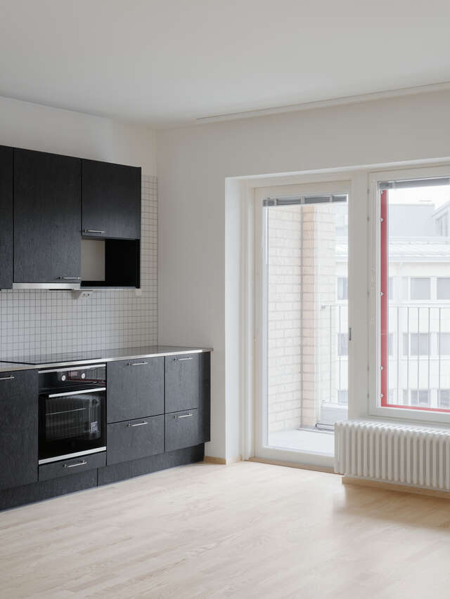 A space with black kitchen on the left and large windows on the right.