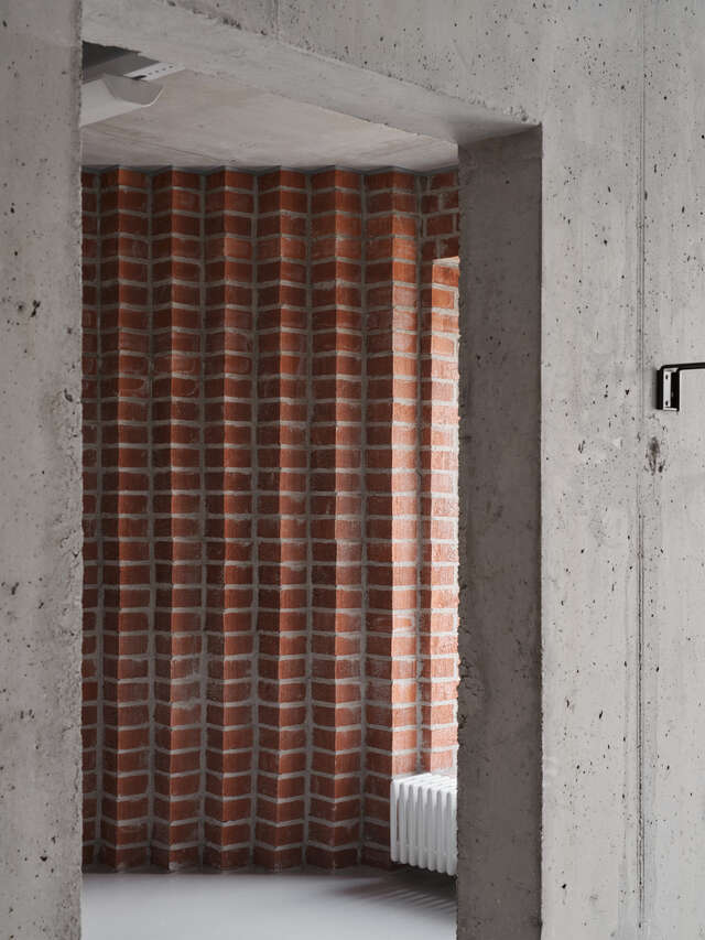 Concrete doorway and red brick relielf behind it.