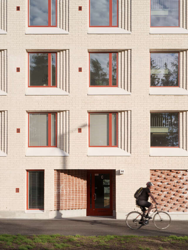 Brick building's entry and square window recesses around it.