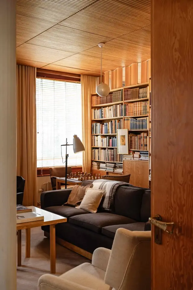 A view from the door towards a cozy room with wooden surfaces and bookshelf