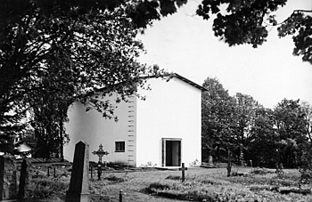 Black and white image of a small and simple white chapel viewed from the churchyard.