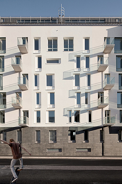 Facade with stone and white plaster elements as well as narrow rectangular windows.