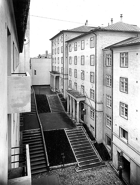 Black and white image of white multiple story buildings with framed windows.