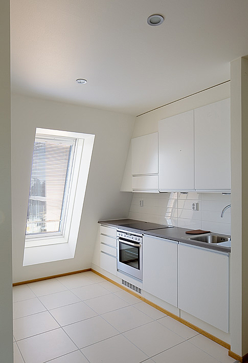White kitchen with a slanted wall.