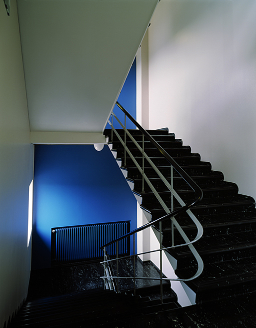 Black and white staircase with blue back wall and black railing.