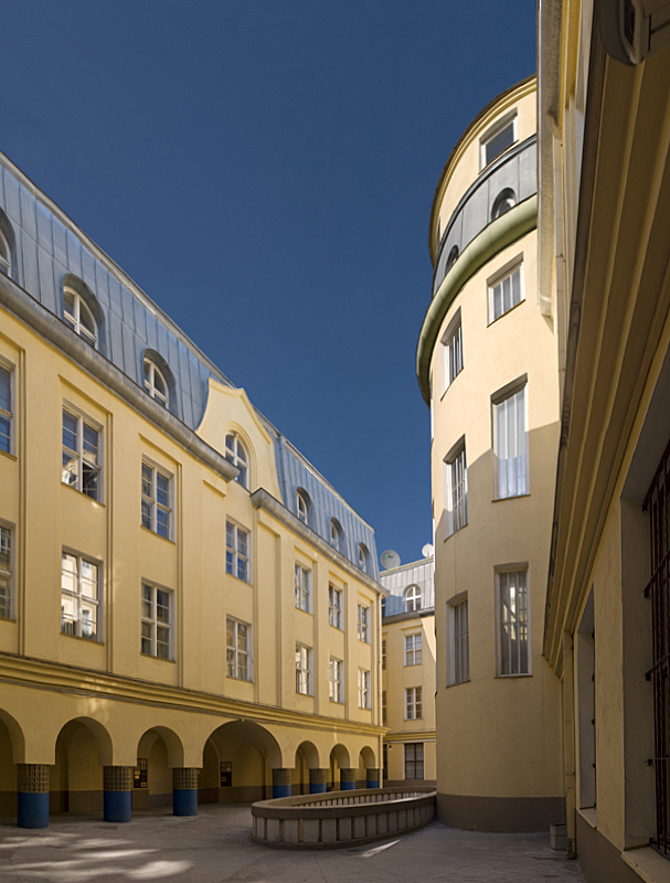 Couryard of yellow building with grid windows and blue roofs.