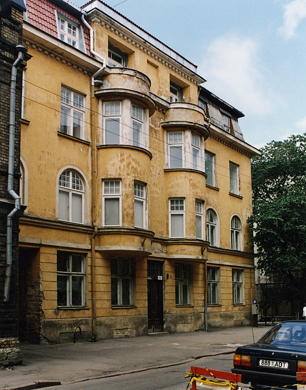 Old yellow multiple storey building with bay windows.