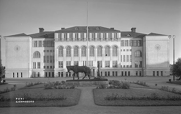 Old picture of a horse statue in front of the white school facade with arch details and other decorative elements.