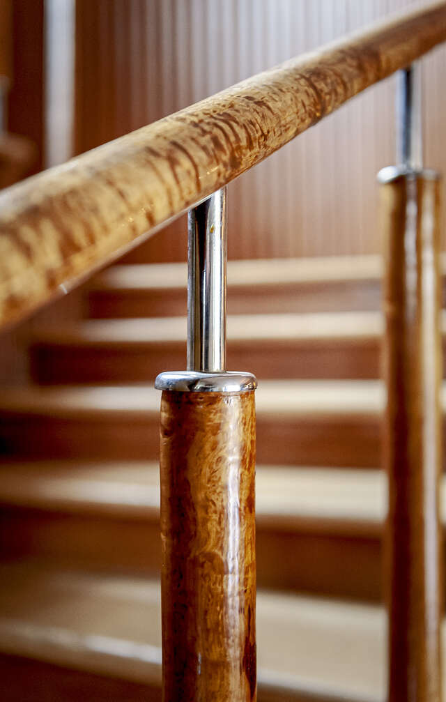 A close-up picture of a wooden railing by the staircase of the Villa Koskikara.
