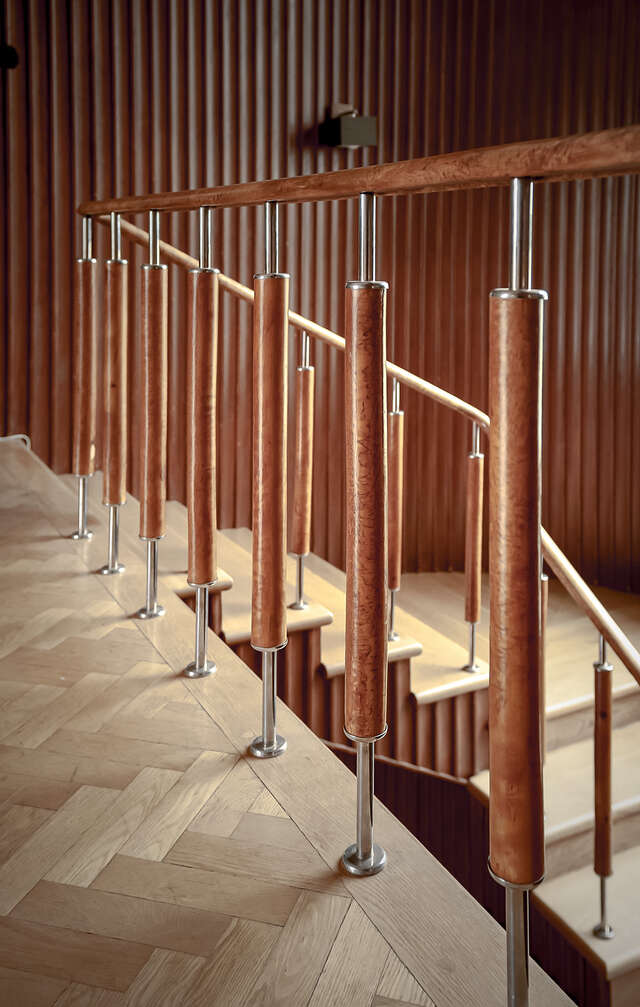 A wooden and metallic handrail by the edge of a higher floor level.