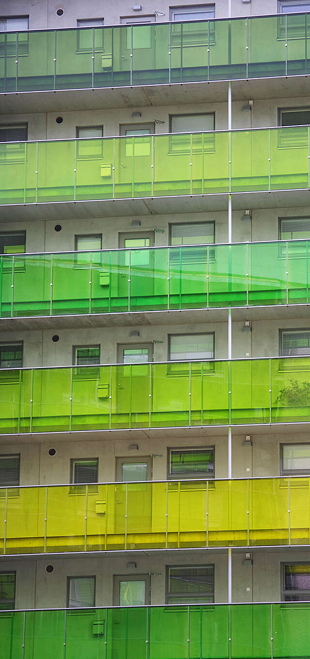 Multiple storey apartment building with green balconies.