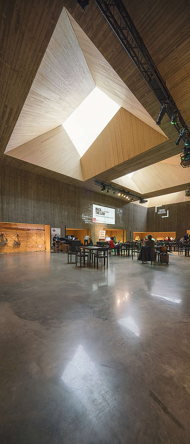 Atrium with concrete floors, a cafeteria and a ceiling window on the wood covered ceiling.