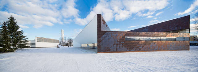 Dark copper of the façade standing out from the whiteness of the surrounding Aalto buildings in a snowy landscape