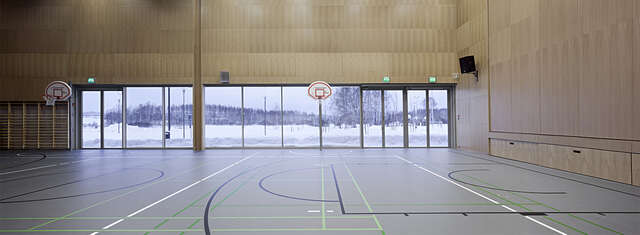 School gymnasium with large windows showing a snow landscape.