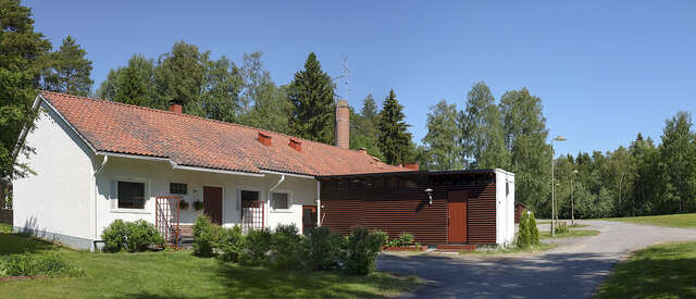 An image of a terraced house. The façade of the house consists of white walls and the pitched roof of red roof bricks.