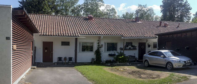 An image of a terraced house. The façade of the house consists of white walls and the pitched roof of red roof bricks.