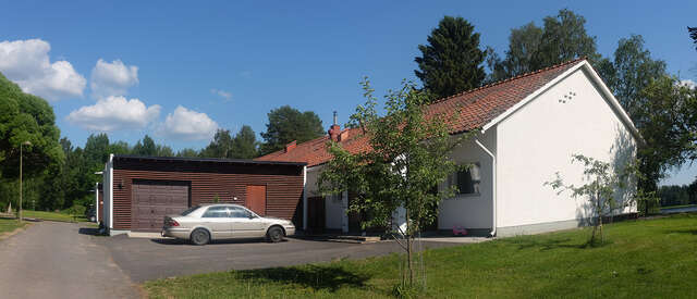 An image of a terraced house. The façade of the house consists of white walls and the pitched roof of red roof bricks.