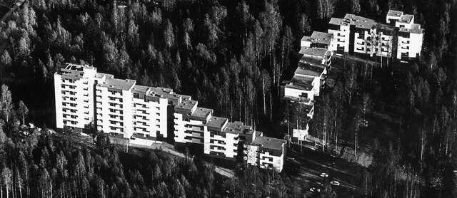 Aerial image of a white apartment block surrounded by forest.
