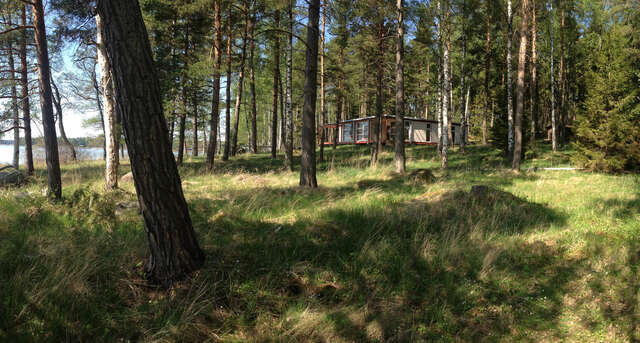 A wooden cabin can be seen behind some trees in al ush green field.