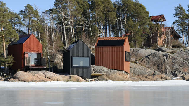 Group of dirrerent-coloured cabins on shoreline rocks