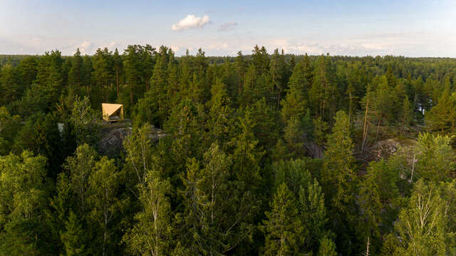 Wooden structure seen from afar in the middle of a dense forest.