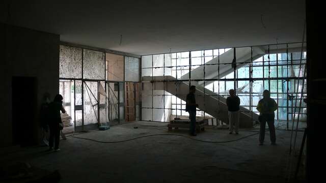 Workers in a dark entrance hall that is very dirty and needs restauration.