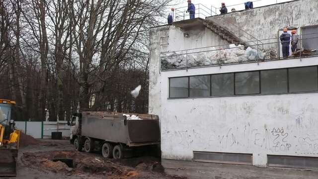 Workers on the roof of the library, a truck is positioned next to the building.