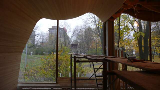 A half-ready room with a workbench and saw in the middle of it, you can see a autumnal yard from the window.