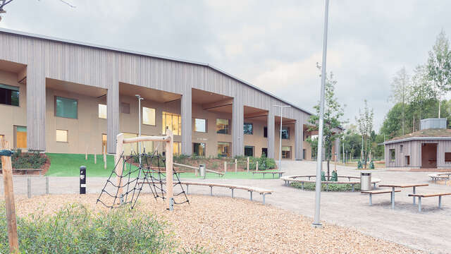 A children's playground with a wooden building behind.