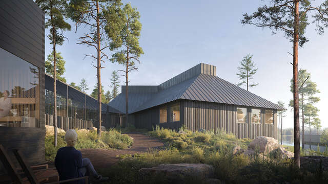 Dark wooden building surrounded by trees. sand walkway with one person in the middle.