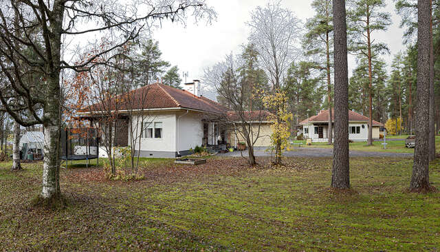 A house with white, plastered walls and a hipped, red brick roof.