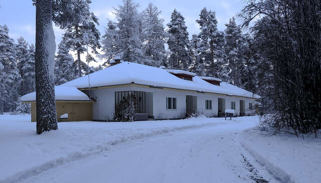 A house with white, plastered façade with entrances decorated with wooden grating.