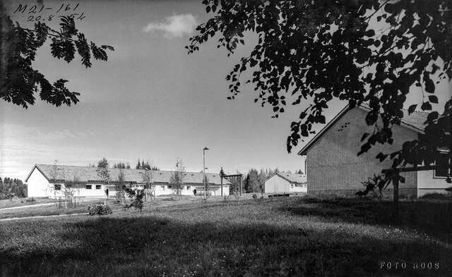 Black and white photo of the terraced house behind a hayfield.