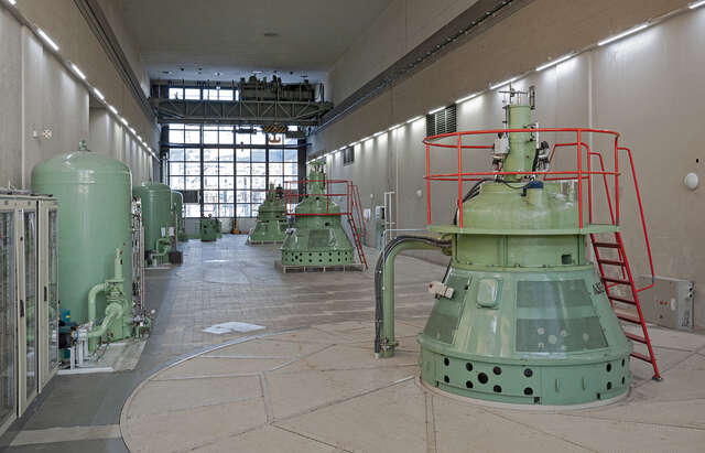 Photo of a room with machinary painted bright green, with windows on the background that let the natural light in.