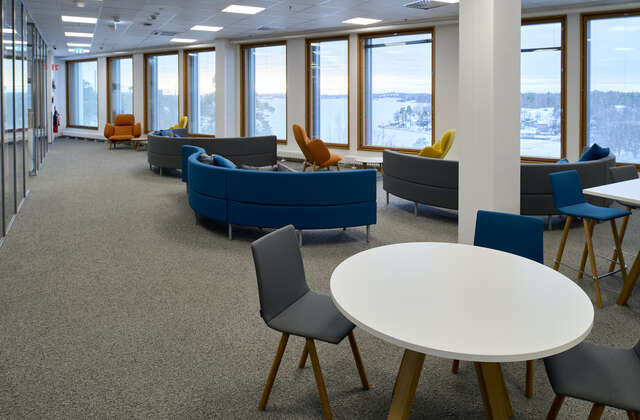 A room with couches and tables, with a row of windows looking outside