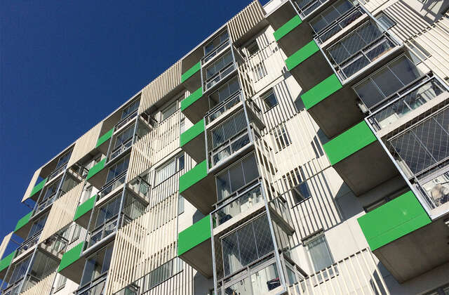 Multiple storey apartment building with green balconies.