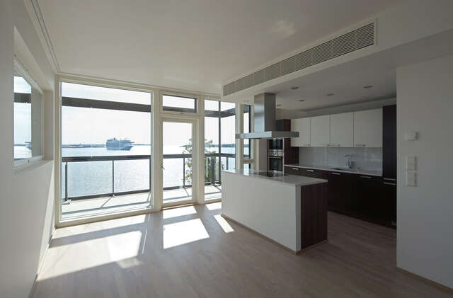 White kitchen with a large windows to the balcony and a view of the sea.