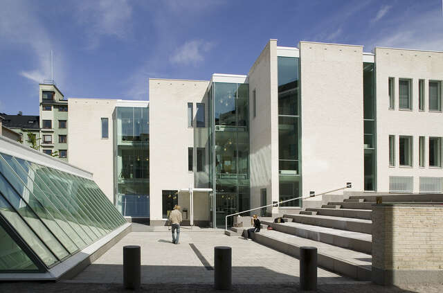 Inner square with a slanted window wall on the left and the tiered building back facade at the back.