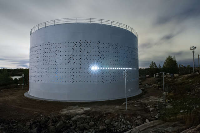 White oil silo with holes in a rocky landscape