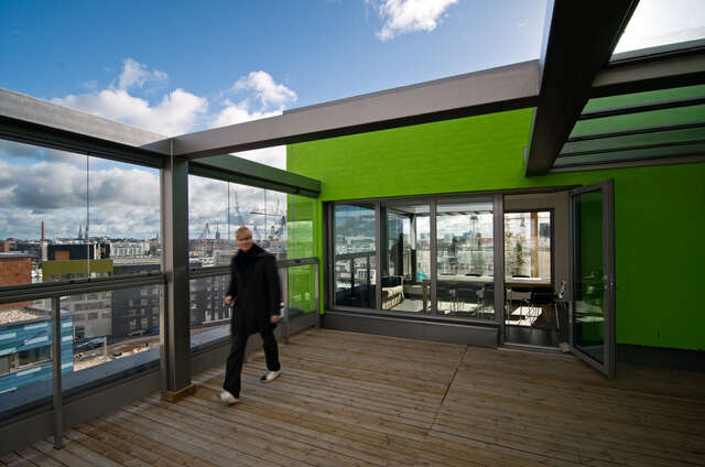 Young man walking on wooden-floored roof terrace next to a lounge room