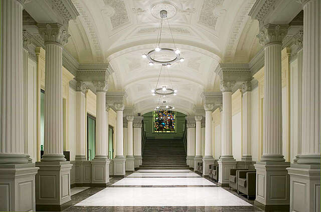 Ornate hallway lined with columns, marble floors and decorative ceiling elements.