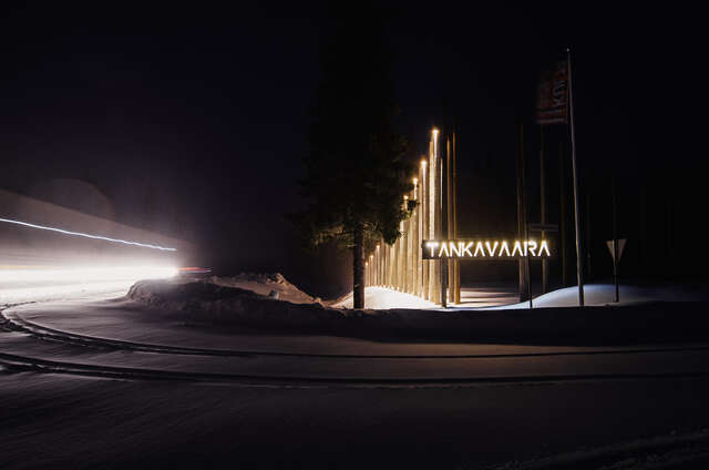 Light poles with sign that reads TANKAVAARA in the middle of darkness.