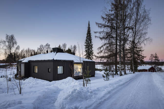A detached house surrounded by snow and trees.